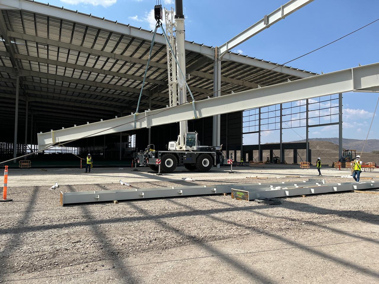 Grúa izando una viga de acero en el montaje de una nave industrial