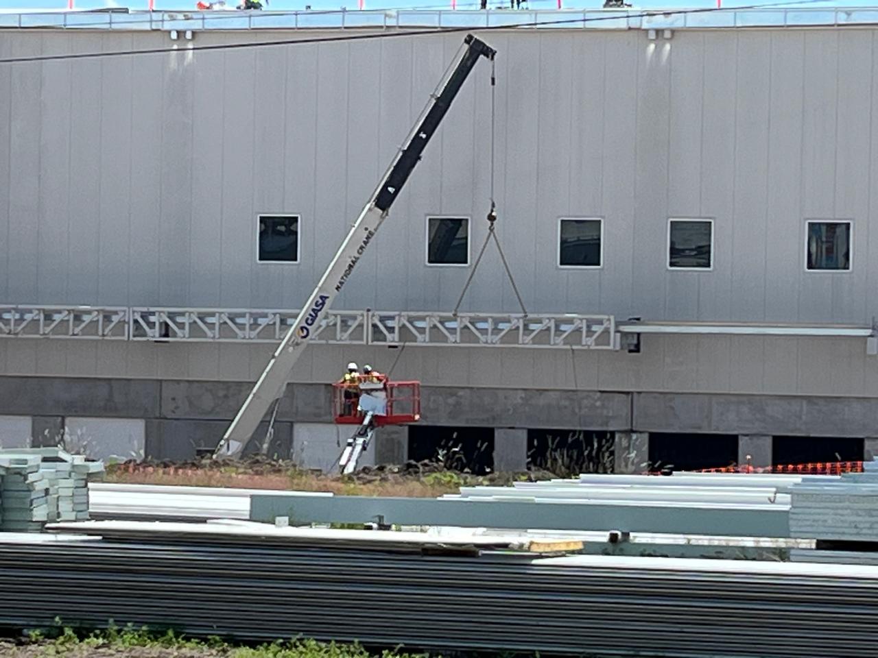 Grúa telescópica trabajando en la fachada de una nave industrial